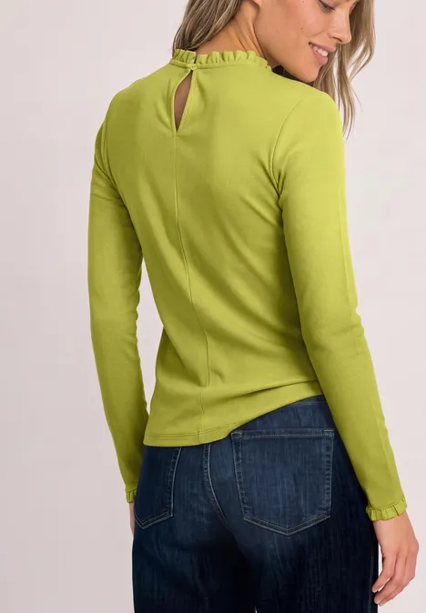 Vrouw van achteren in groene trui met lange mouwen en blauwe spijkerbroek