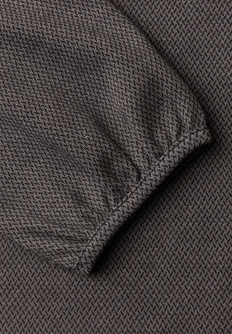 Nahaufnahme eines graubraunen, gestrickten Ärmels mit elastischer Manschette