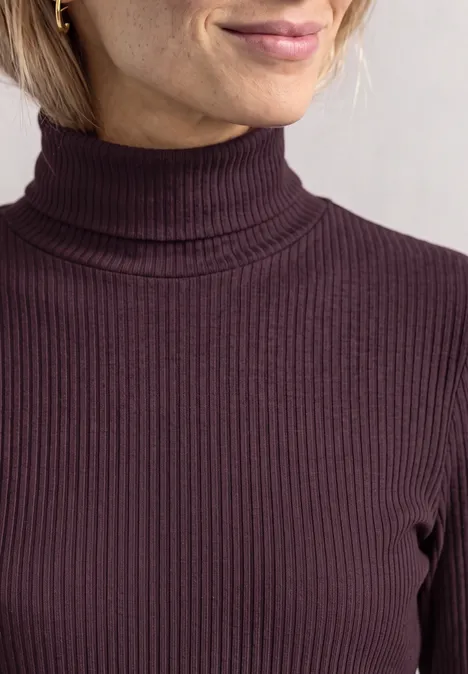Vorderansicht eines dunkelvioletten, fein gerippten Rollkragen-Pullovers am Oberkörper einer Frau.