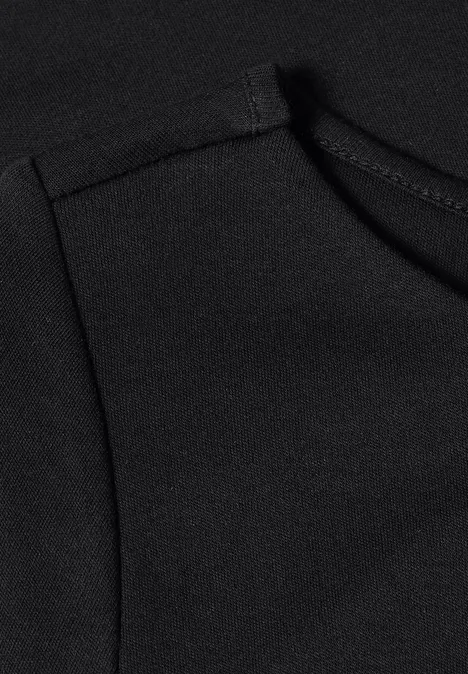 T-shirt basique à col bateau Black Nahaufnahme einer schwarzen Stofffläche mit Nahtdetail und dekorativer Kurve.