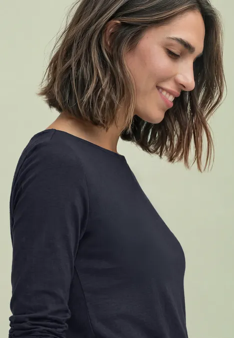 Basic Shirt mit U-Boot-Ausschnitt indigo night Eine lächelnde Frau in schwarzem Langarmshirt, im Profil nach unten blickend.