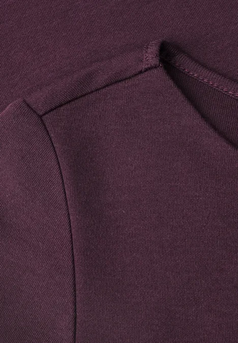 Nahaufnahme eines dunkelvioletten Sweatshirts mit seitlicher Eingrifftasche und weichem Stoff