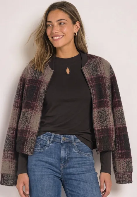 Shirt mit Turtle Neck und Schlitzdetail black coffee Frau mit lässiger karierter Jacke, schwarzem Oberteil und Jeans, die seitlich lächelnd posiert.