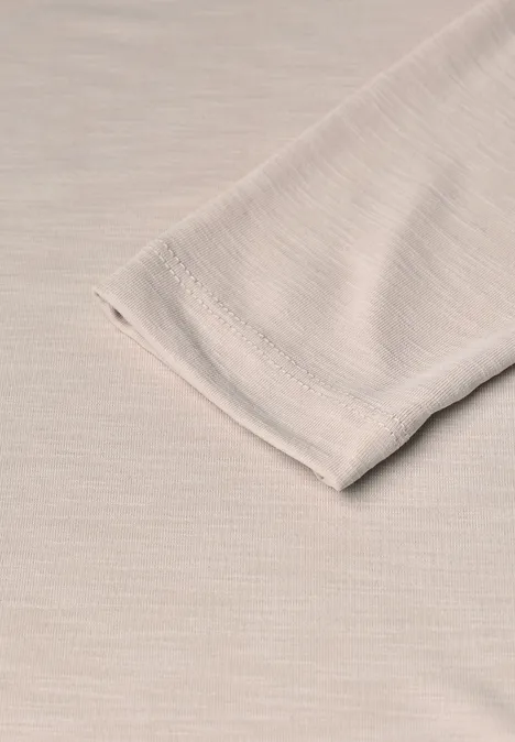 Close-up van een beige mouwuiteinde op een beige, fijn geribbeld textiel.