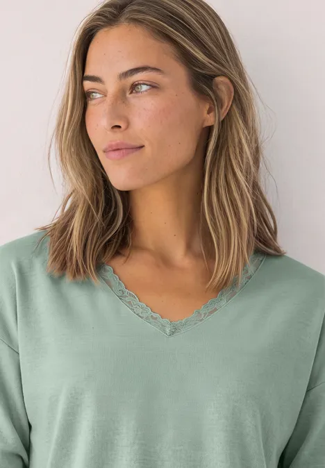 Langarm Shirt mit V-Neck und Spitzendetail eucalyptus green Junge Frau in hellgrünem V-Ausschnitt-Shirt mit Spitzenbesatz schaut seitlich.