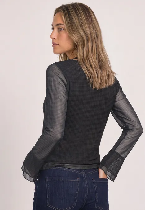 Shirt aus Mesh mit langen Volant-Ärmeln black coffee Eine Frau steht seitlich, trägt einen schwarzen Pullover mit transparenten Ärmeln und blaue Jeans.