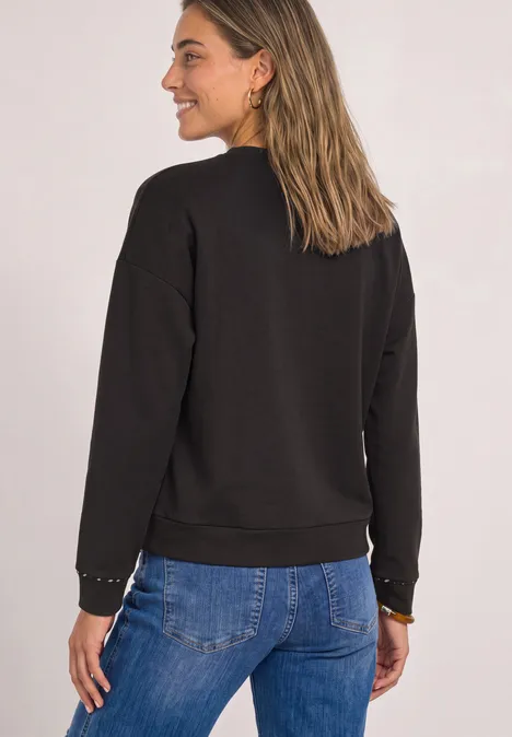 Langarm Shirt mit Rehprint-Details black coffee Frau von hinten in schwarzem Sweatshirt und blauer Jeans, lächelnd und schulterlangem Haar.