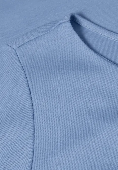 Nahaufnahme eines hellblauen T-Shirts oder Oberteils mit erkennbarer Schulternaht.