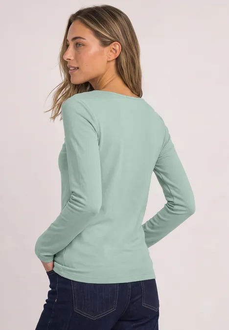 T-shirt basique à col bateau eucalyptus green Frau von hinten in mintgrünem Langarmshirt und Jeans.