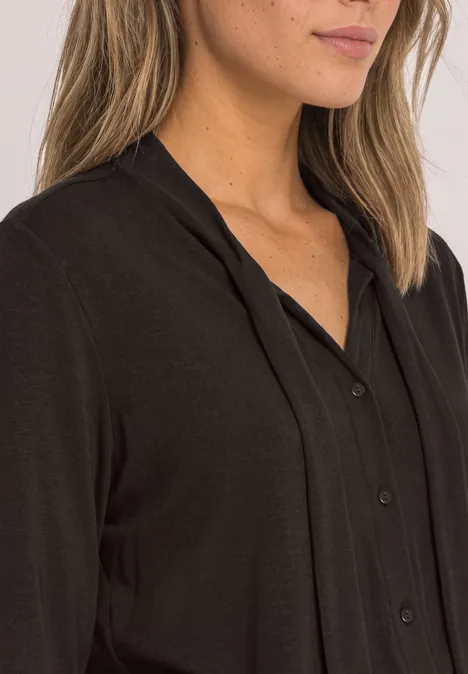 Schwarze Bluse mit Knopfleiste und V-Ausschnitt aus weichem, fließendem Stoff.