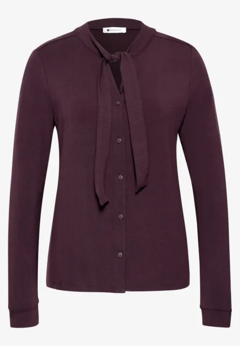 Lila Strickjacke mit Knopfleiste und Schleifenkragen, langärmlig.