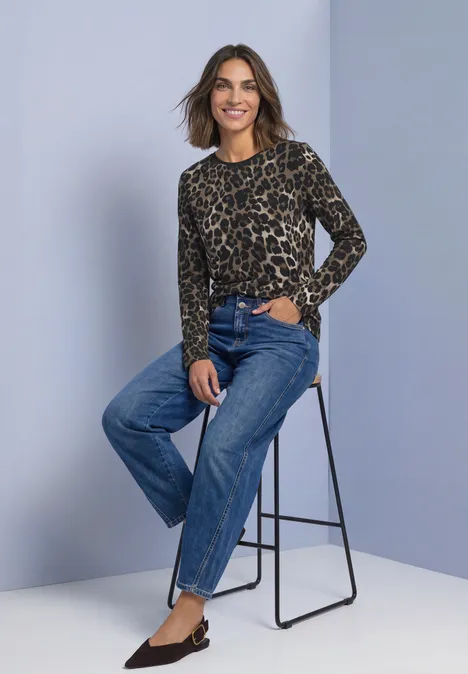 Langarm Shirt mit Rundhals und Leo-Muster Black Frau auf Barhocker in Leo-Pullover und weiten Jeans, lächelt, schlanke schwarze Ballerinas.