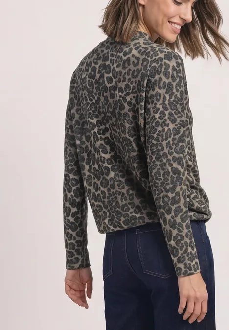 Frau trägt lockeres, langärmeliges Oberteil mit Leopardenmuster und dunkle Jeans von hinten.