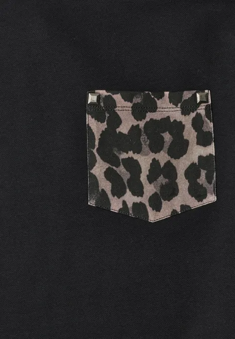 Schwarzes Gewebe mit einer aufgenähten Tasche im grauen Leopardenmuster.