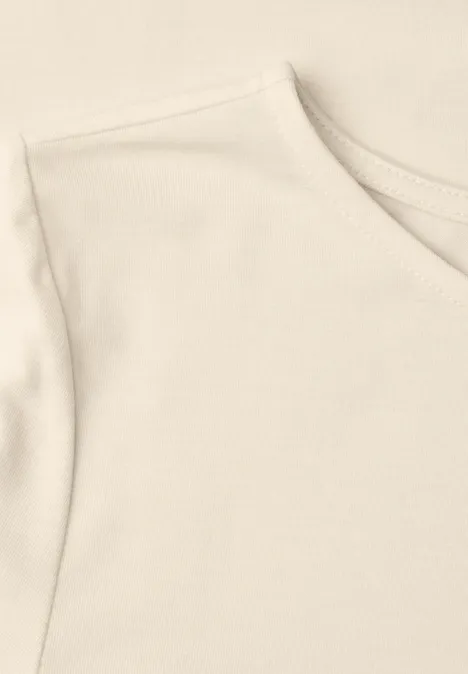 Close-up van een lichtbeige katoenen T-shirt met ronde hals en korte mouw.