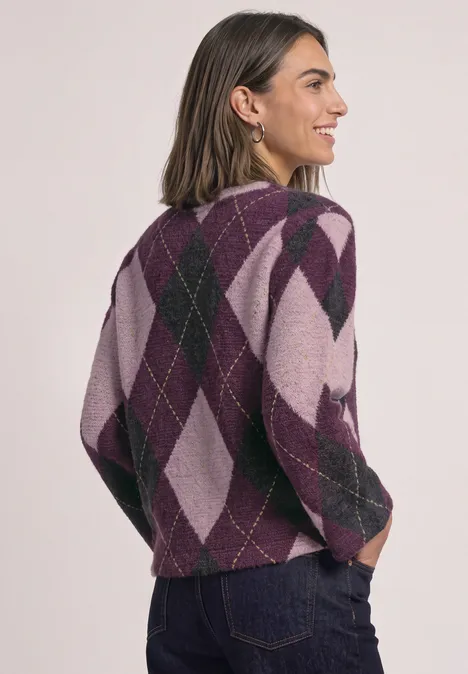 Frau in violett-rosafarbenem Argyle-Pullover zeigt Rückansicht, trägt Jeans.