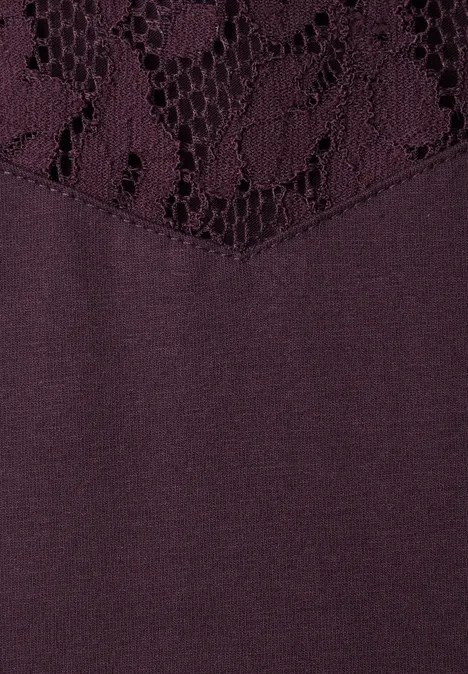Top mit Rundhals und Spitze berry plum Nahaufnahme eines lila Kleidungsstücks mit Spitzenbesatz und glatter Stoffstruktur darunter.