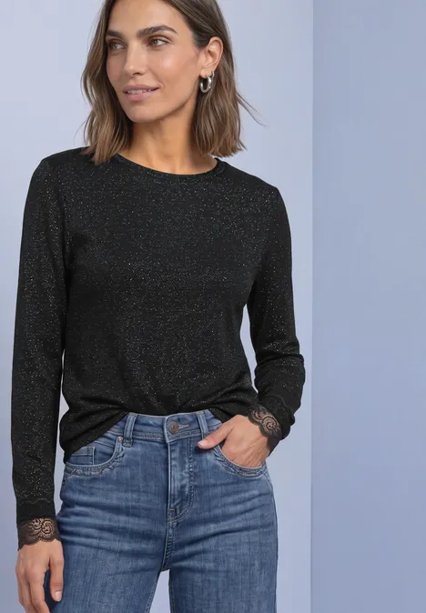 T-shirt à manches longues avec paillettes et dentelle Black Femme portant un pull noir scintillant à manches longues avec finition en dentelle, associé à un jean.
