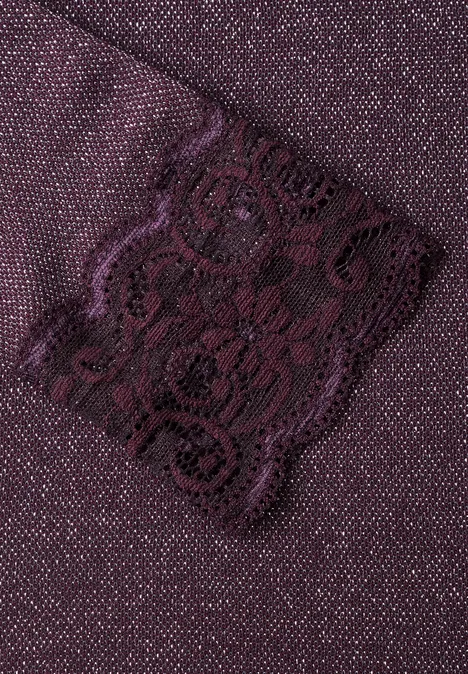 Nahaufnahme eines violetten Stoffes mit floraler Spitzenapplikation.