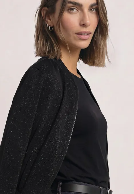 Junge Frau in schwarzem Top und Blazer vor hellem Hintergrund
