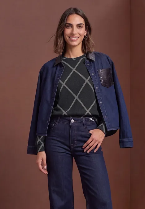 T-shirt à manches longues, col rond et motif à carreaux armor grey Femme souriante portant une veste en jean sombre sur les épaules, un pull à carreaux et un jean sur fond marron.