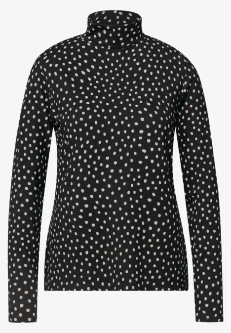 Ein schwarzer Rollkragenpullover mit weißem Pünktchenmuster.