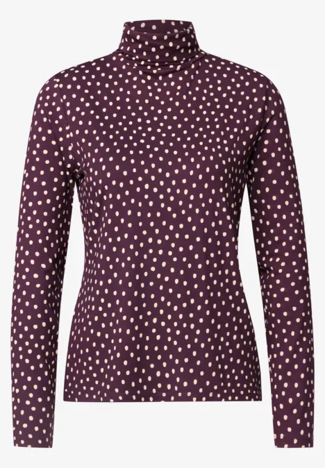 Ein langärmliger Rollkragenpullover in dunklem Rot mit kleinem hellen Herzmuster.