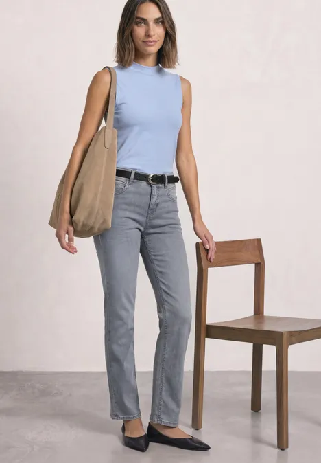 Basic top cashmere blue Frau trägt hellblaues Top, graue Jeans, schwarze Ballerinas und große Schultertasche vor hellem Hintergrund.