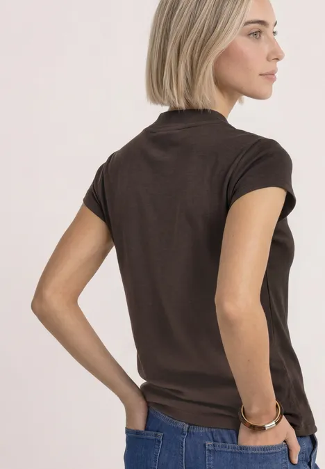 Basic Shirt mit Turtle Neck espresso brown Frau im Profil mit blondem Bob trägt braunes T-Shirt und Jeans vor neutralem Hintergrund.