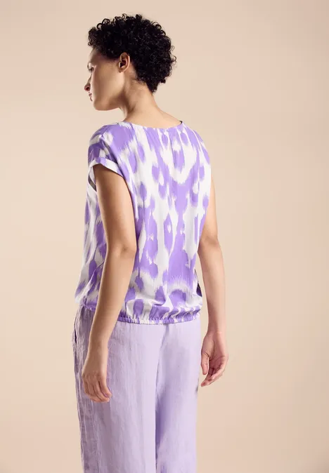 Viskose Bluse smell of lavender Frau mit lila gemustertem Oberteil und Hose, von hinten fotografiert.
