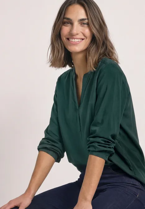 Tuniek met V-hals shadow teal Lächelnde Frau mit schulterlangem Haar in grüner Bluse und Jeans