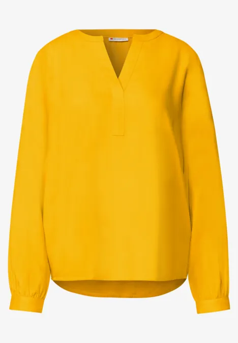 Gelbe Damenbluse mit V-Ausschnitt und langen Ärmeln.