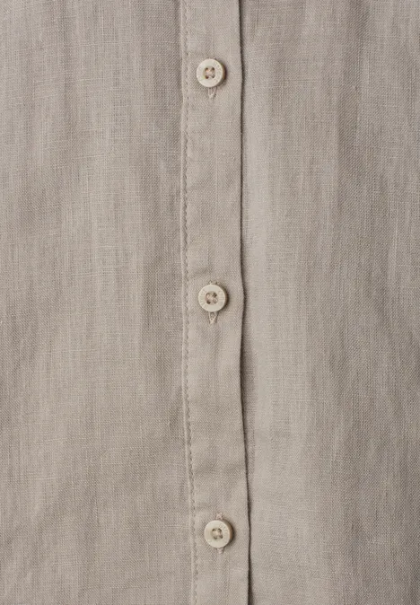 Nahaufnahme eines beige-grauen Leinenhemds mit Knopfleiste und cremefarbenen Knöpfen.