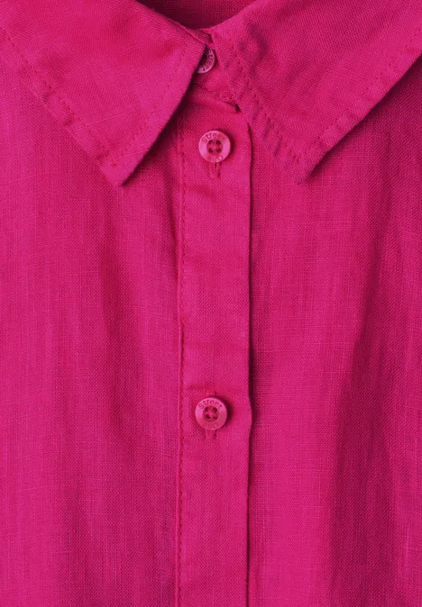 Close-up van een roze overhemd met kraag, knoopsluiting en twee zichtbare knopen.