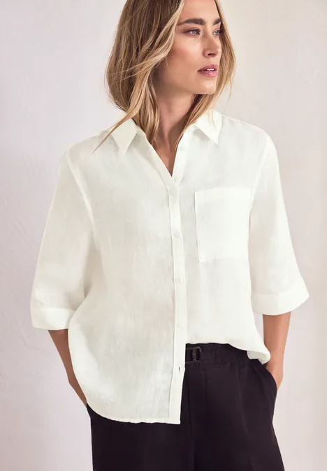 Weißes Leinenhemd mit 3/4-Ärmeln, schwarze Hose, schlichtes Outfit.