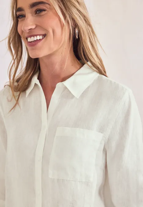 Weibliche Person in weißer Leinenbluse mit Kragen und Brusttasche, offenem Ausschnitt.