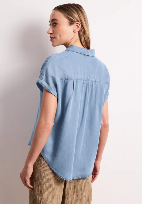 Blouse met overhangende schouders in denimlook Light Blue soft wash Vrouw van achter in lichtblauw jeanshemd met korte mouwen.