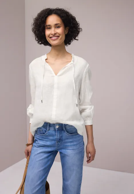 Vrouw in witte blouse en spijkerbroek voor neutrale achtergrond