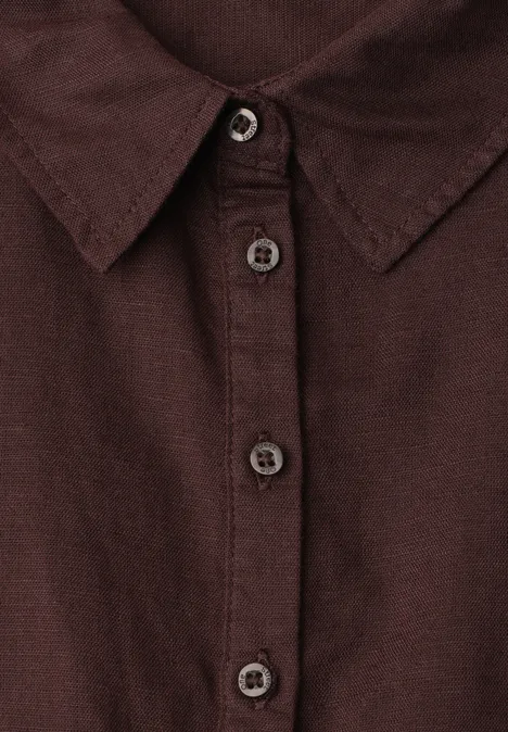 Nahaufnahme eines dunkelbraunen Hemdes mit Stehkragen und Knopfleiste.