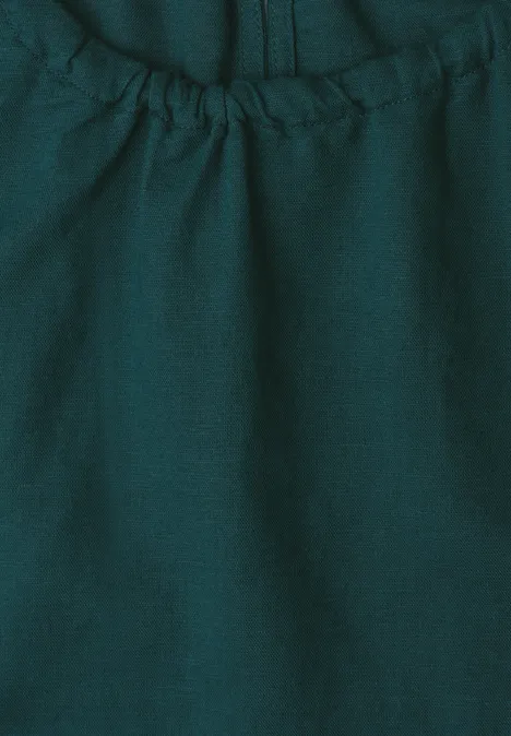 Nahaufnahme eines dunkelgrünen, elastisch gerafften Stoffs mit Naht und feiner Textur.