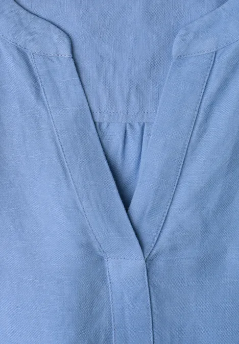 Lichtblauwe V-hals met fijne naden, waarschijnlijk onderdeel van een bovenstuk.