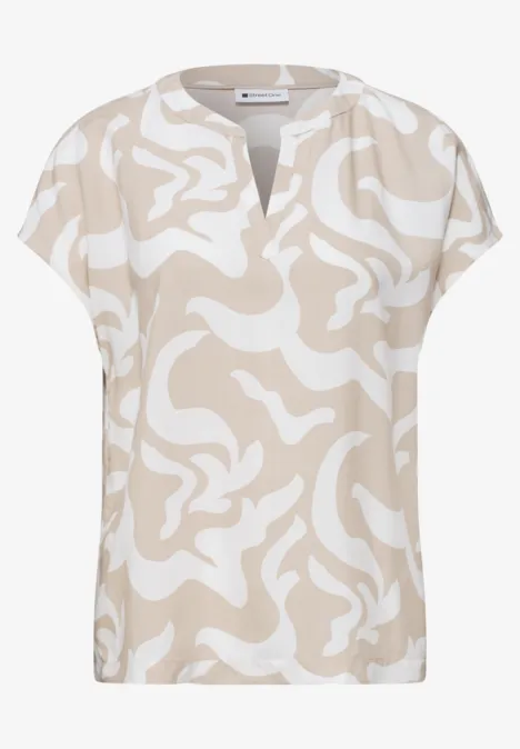 Blouse à manches courtes beige et blanche avec motif abstrait ondulé et encolure en V.