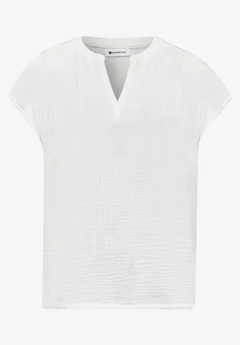 Witte, kortermelige damestop van licht gestructureerd katoen met V-hals.