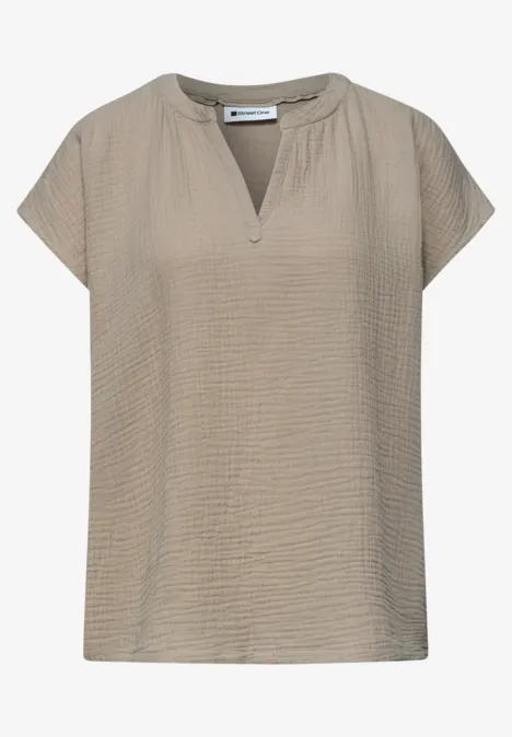 Beige damesblouse met gestructureerde stof, korte mouwen en een kleine V-hals.