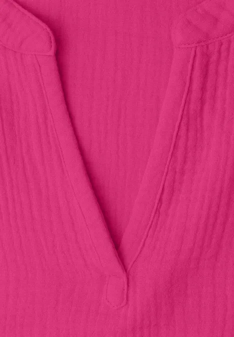 Nahaufnahme eines pinken V-Ausschnitt-Oberteils aus strukturiertem Stoff.