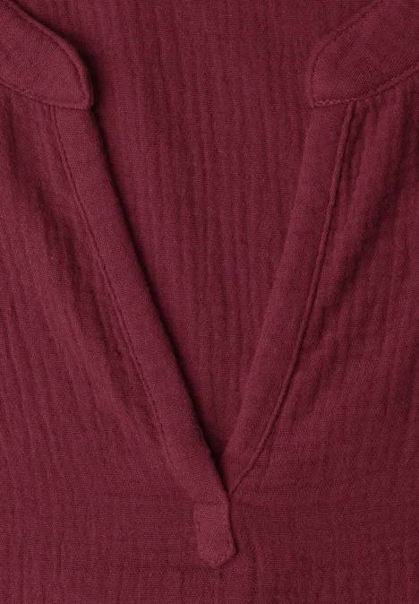 Detailaufnahme eines dunkelroten V-Ausschnitt-Shirts aus strukturiertem Stoff.