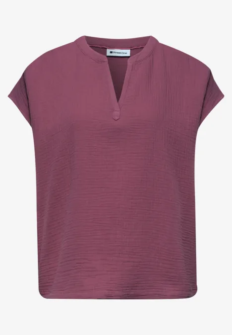 Haut femme violet à manches courtes évasées et encolure en V avec fente discrète.