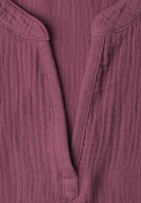 Gros plan d’un haut bordeaux en coton texturé avec encolure en V et col mao.