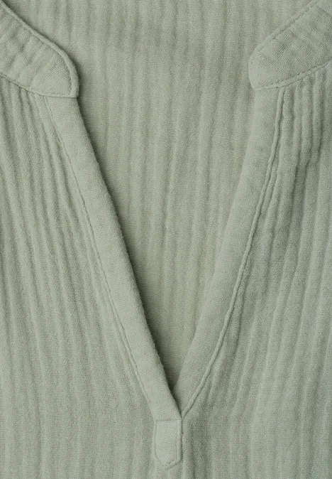 Close-up van een groen, geribbeld V-hals top van zachte stof.