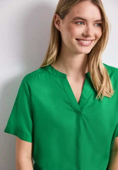 Person trägt grüne Kurzarmbluse mit V-Ausschnitt.